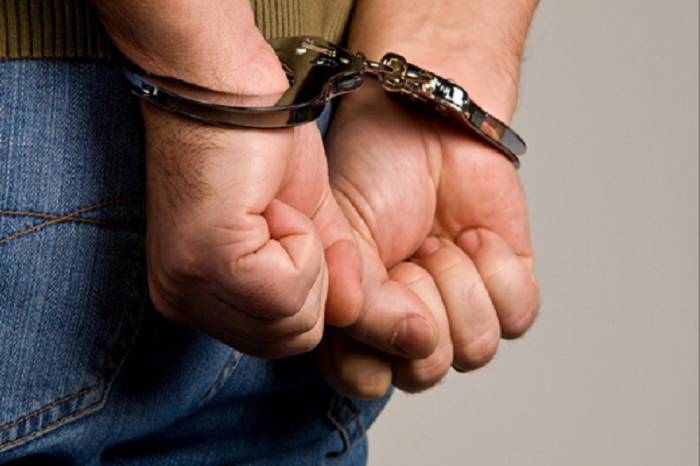 Hombre esposado con las manos en la espalda durante una detención